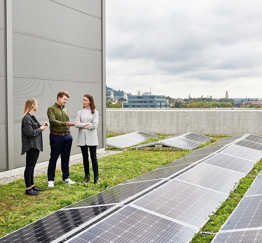 Mitarbeitende die auf einem Dach stehen uns sich über Photovoltaik unterhalten 