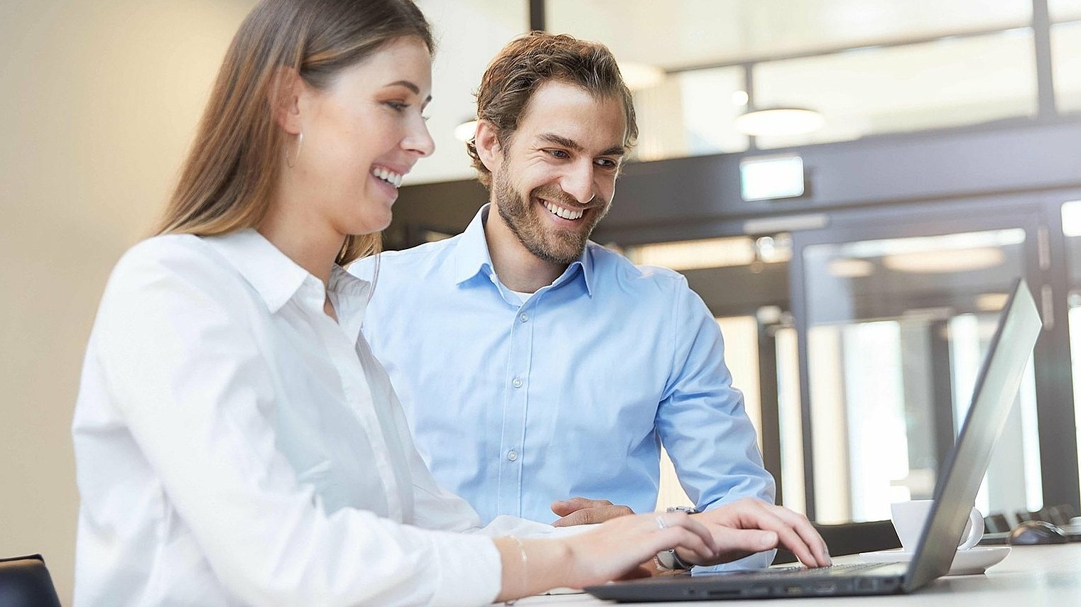 Woman and man reviewing regulatory support documents on laptop