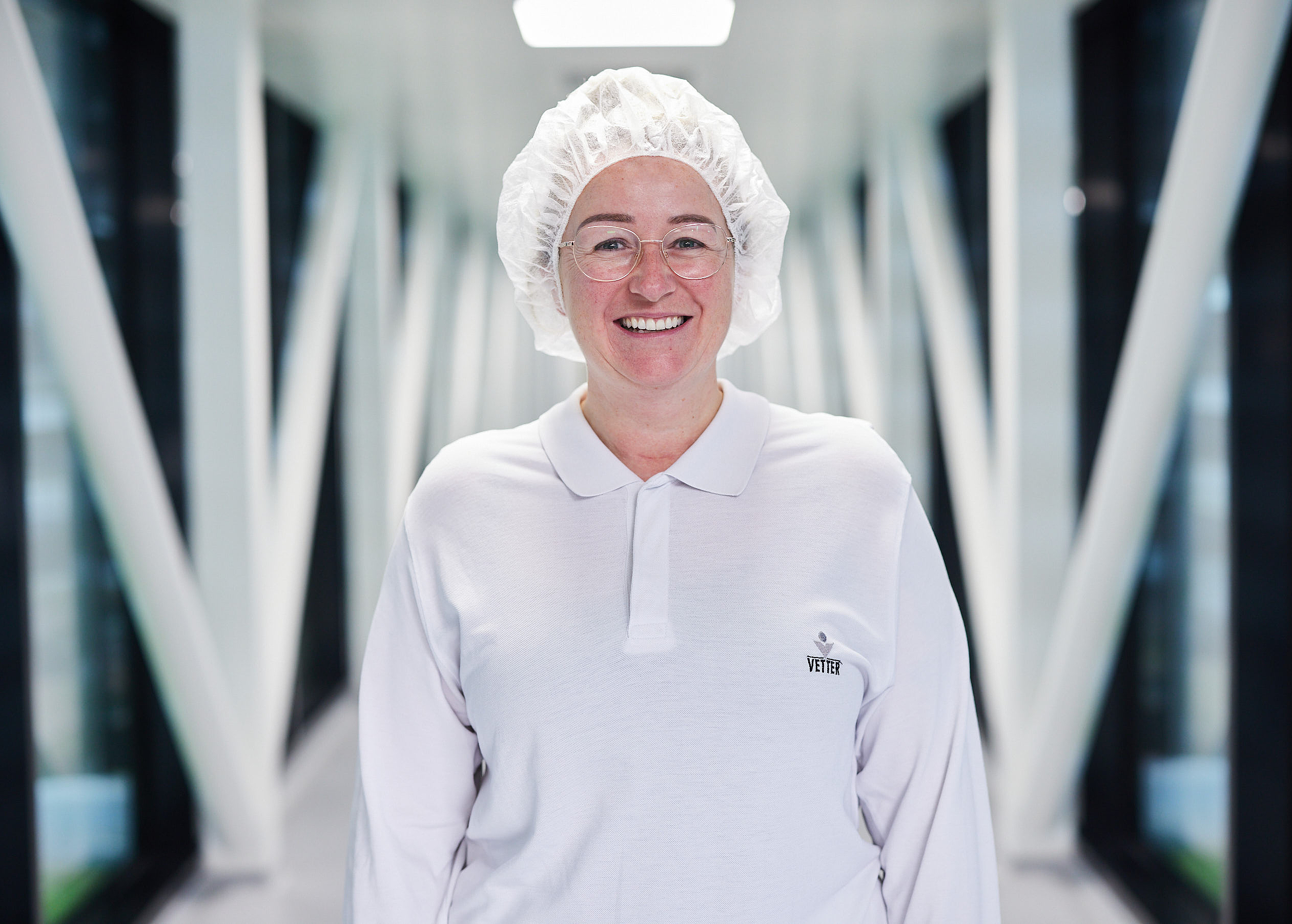 Portraitbild von einer Mitarbeiterin in Laborkleidung  