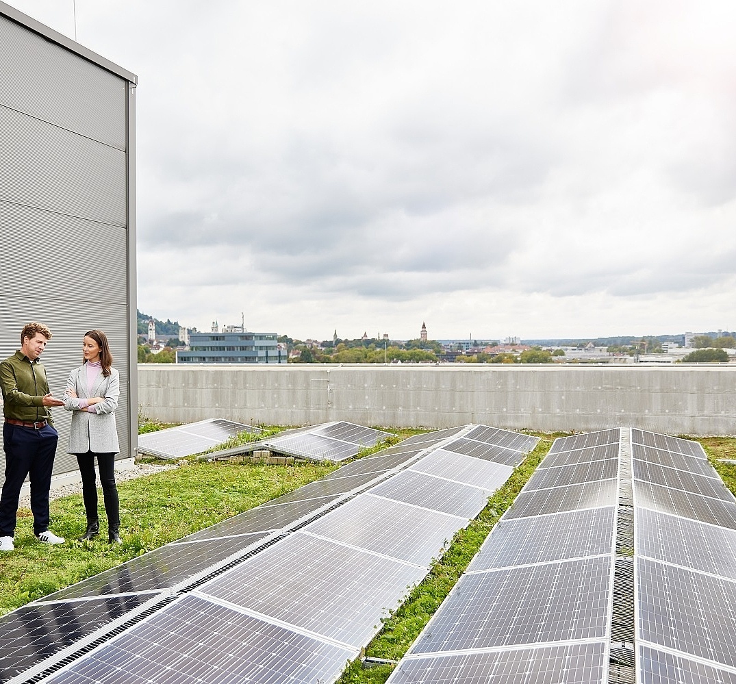 Mitarbeitende die auf einem Dach stehen uns sich über Photovoltaik unterhalten