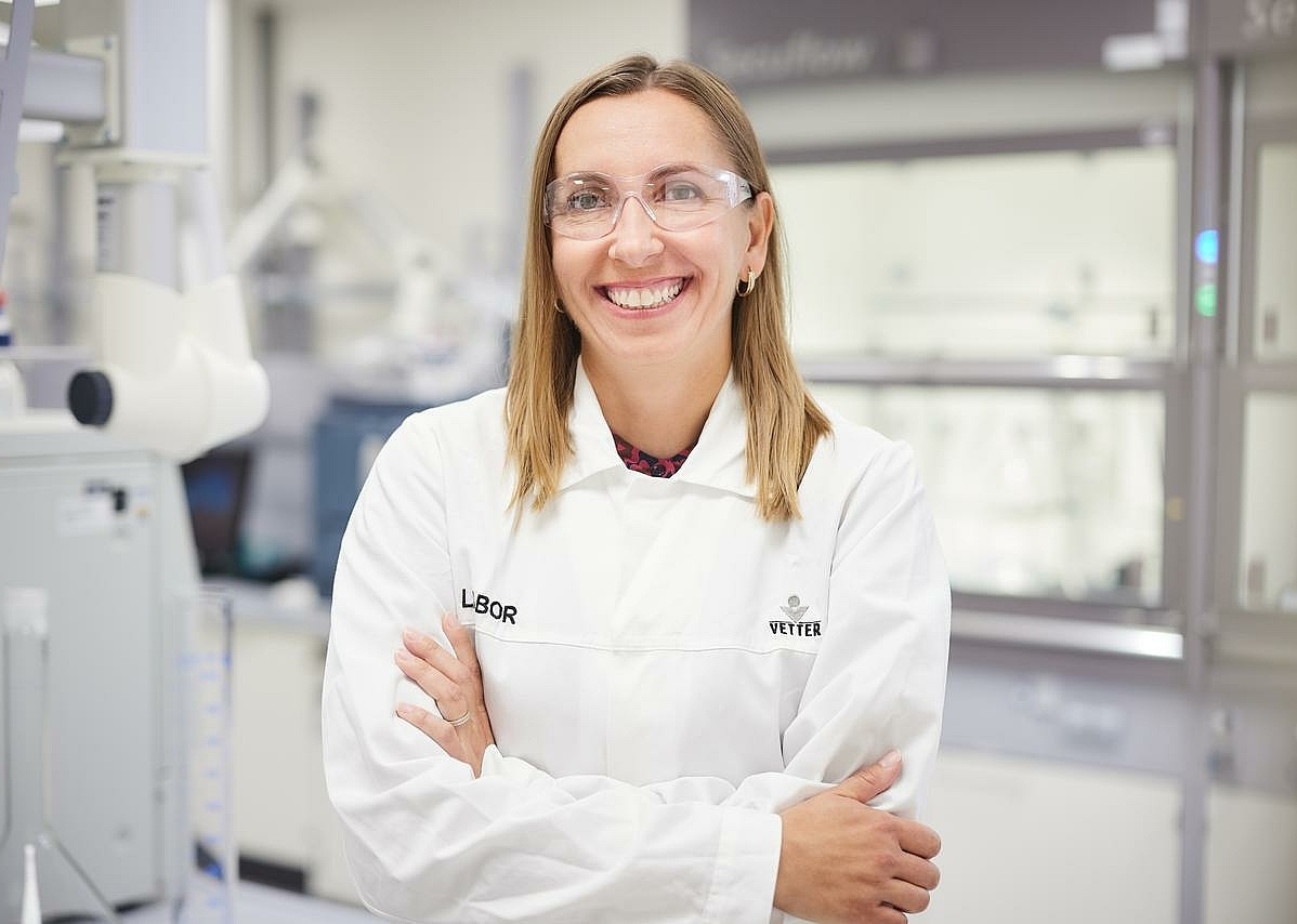 Eine lächelnde Mitarbeiterin in Laborkleidung im Labor 