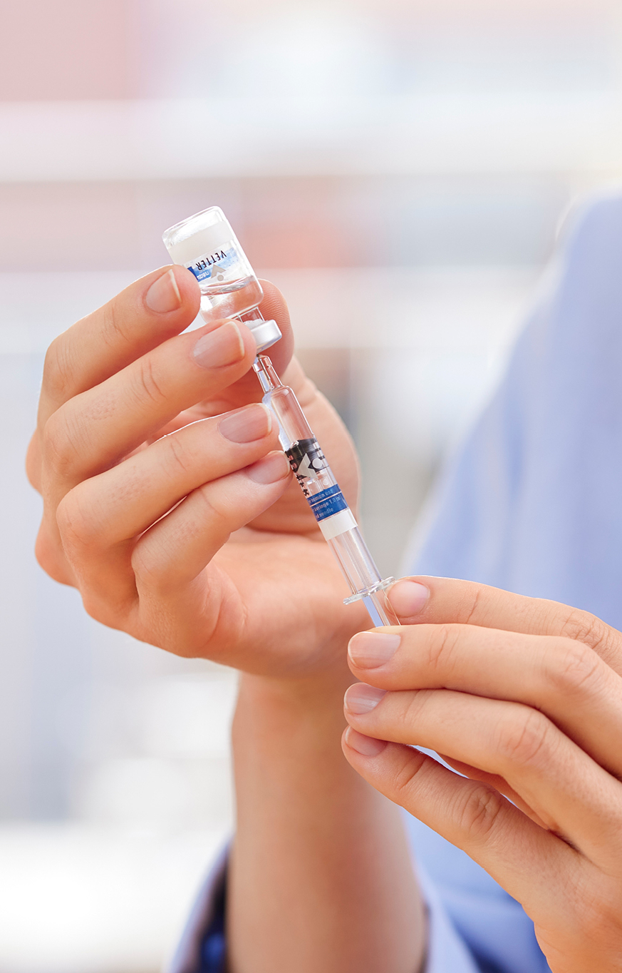 Frau zieht eine Spritze an einem Vial auf