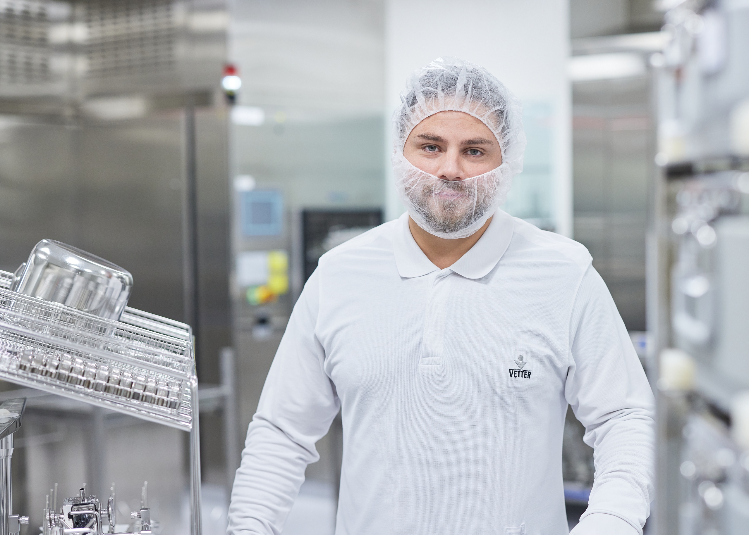 Produktionsmitarbeiter an seinem Arbeitsplatz in Laborkleidung 