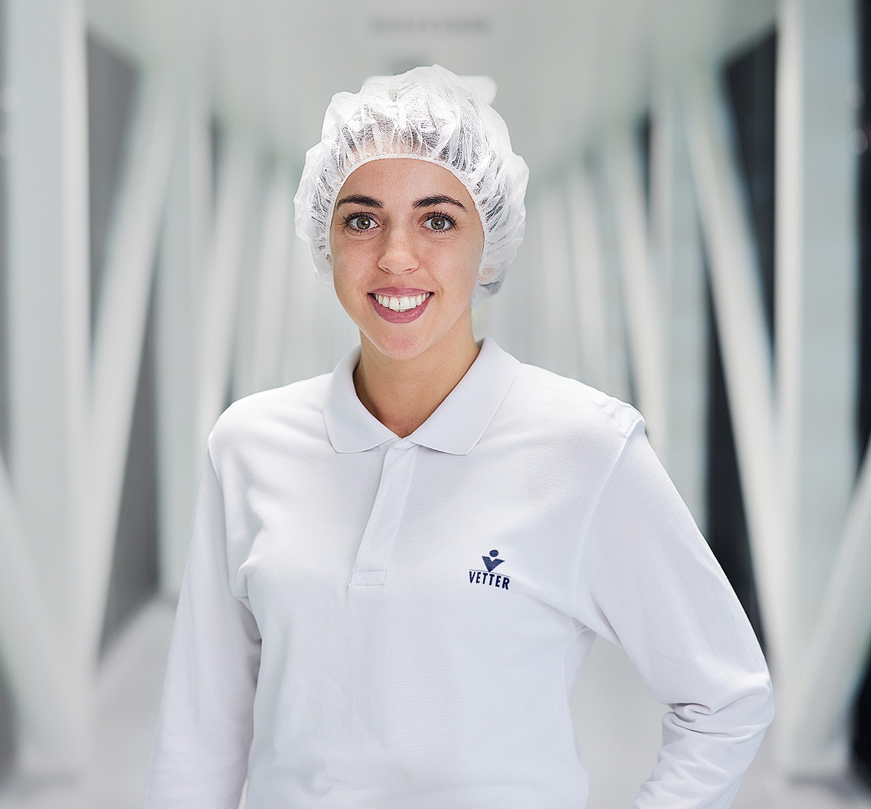 Eine Vetter-Produktionsmitarbeiterin steht in einem Flur in einem Produktionsgebäude