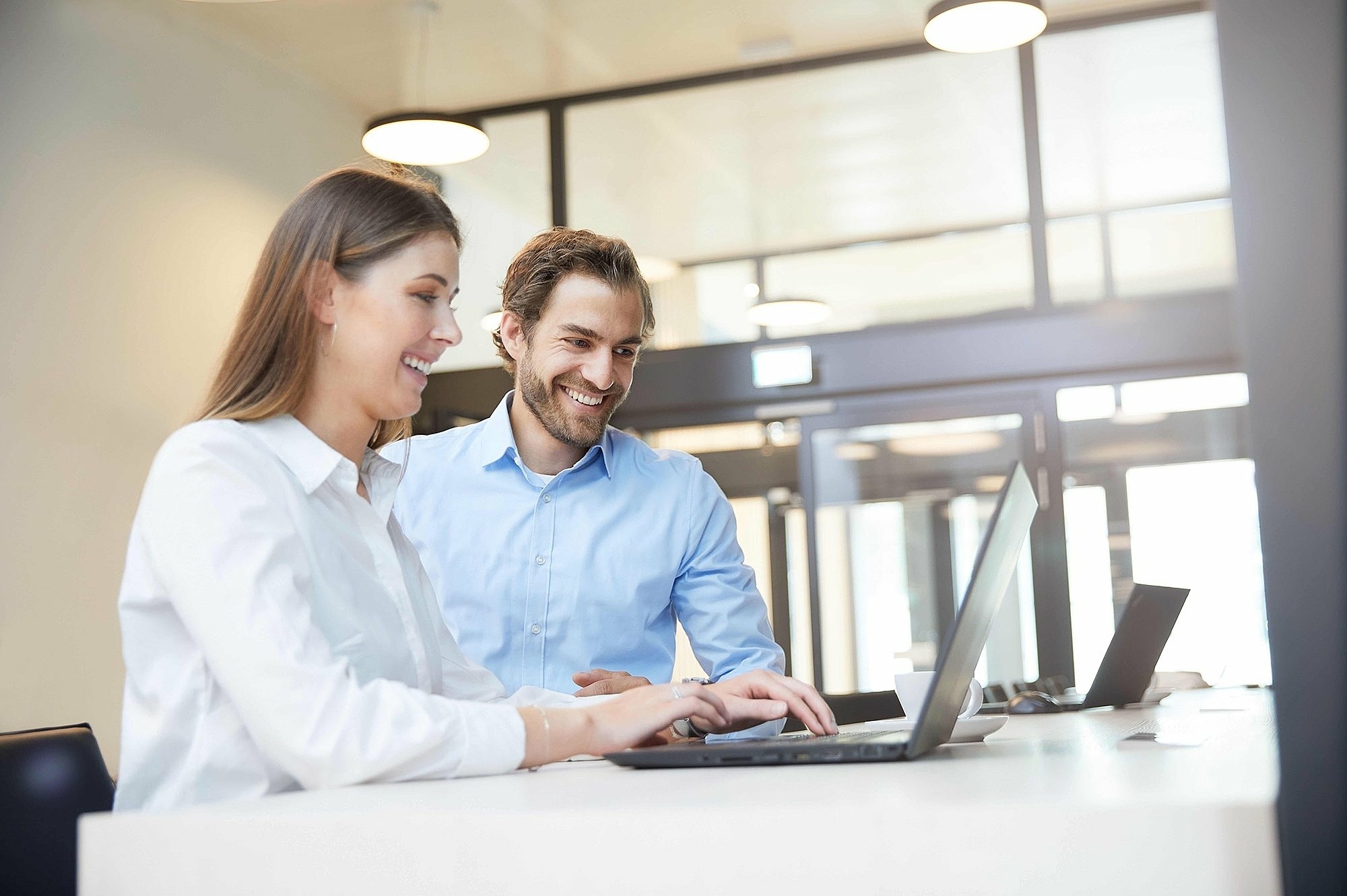 Woman and man reviewing regulatory support documents on laptop
