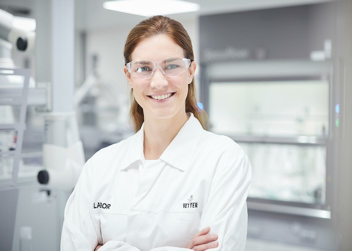 Eine lächelnde Mitarbeiterin in Laborkleidung im Labor 