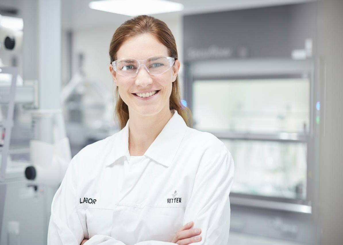 Eine lächelnde Mitarbeiterin in Laborkleidung im Labor 