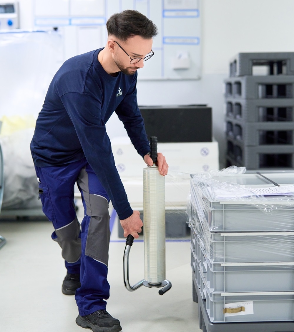 Mitarbeiter Produktionslogistik wickelt Ware in Folie ein