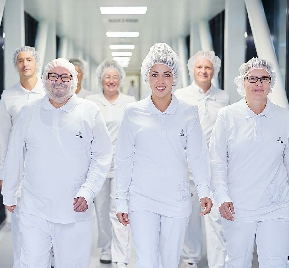 Pharma-Mitarbeitende laufen zusammen einen Flur entlang