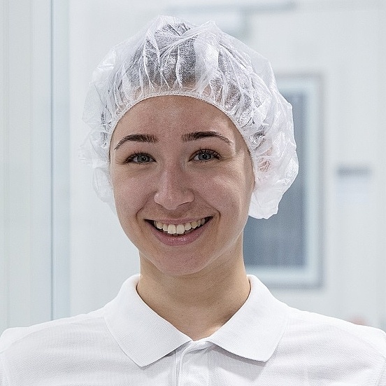 Auszubildende Leonie wird Pharmakantin bei Vetter und steht in Reinraumkleidung vor dem Labor