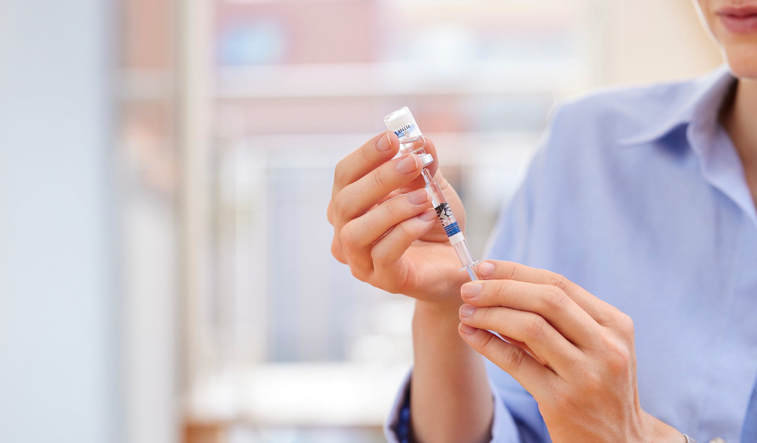 Frau zieht eine Spritze an einem Vial auf