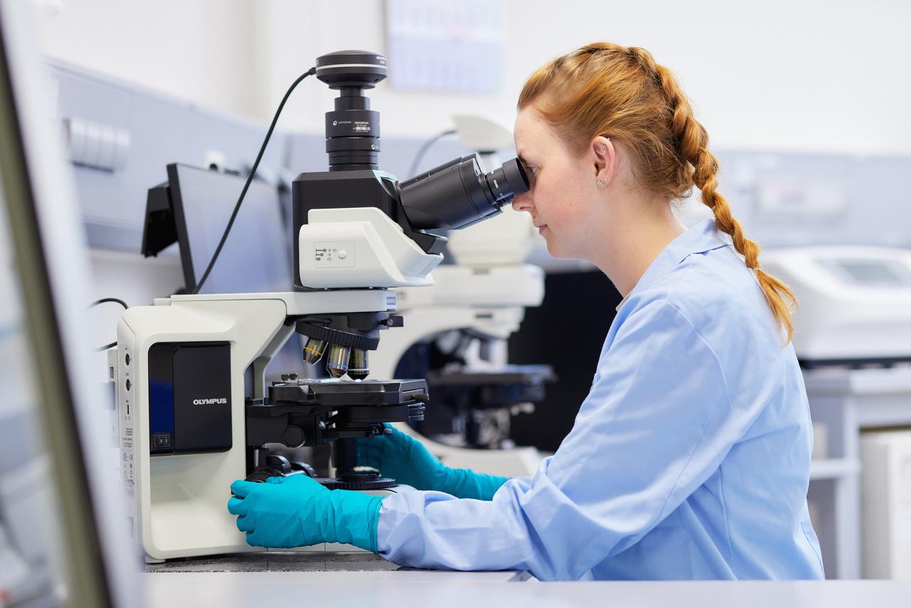 Eine Mitarbeiterin in der Mikrobiologie beim Mikroskopieren