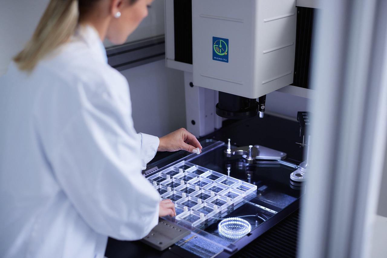 Eine Mitarbeiterin des Packmittellabors in der Qualitätskontrolle bereitet eine hochauflösende kamerabasierte Maschine vor