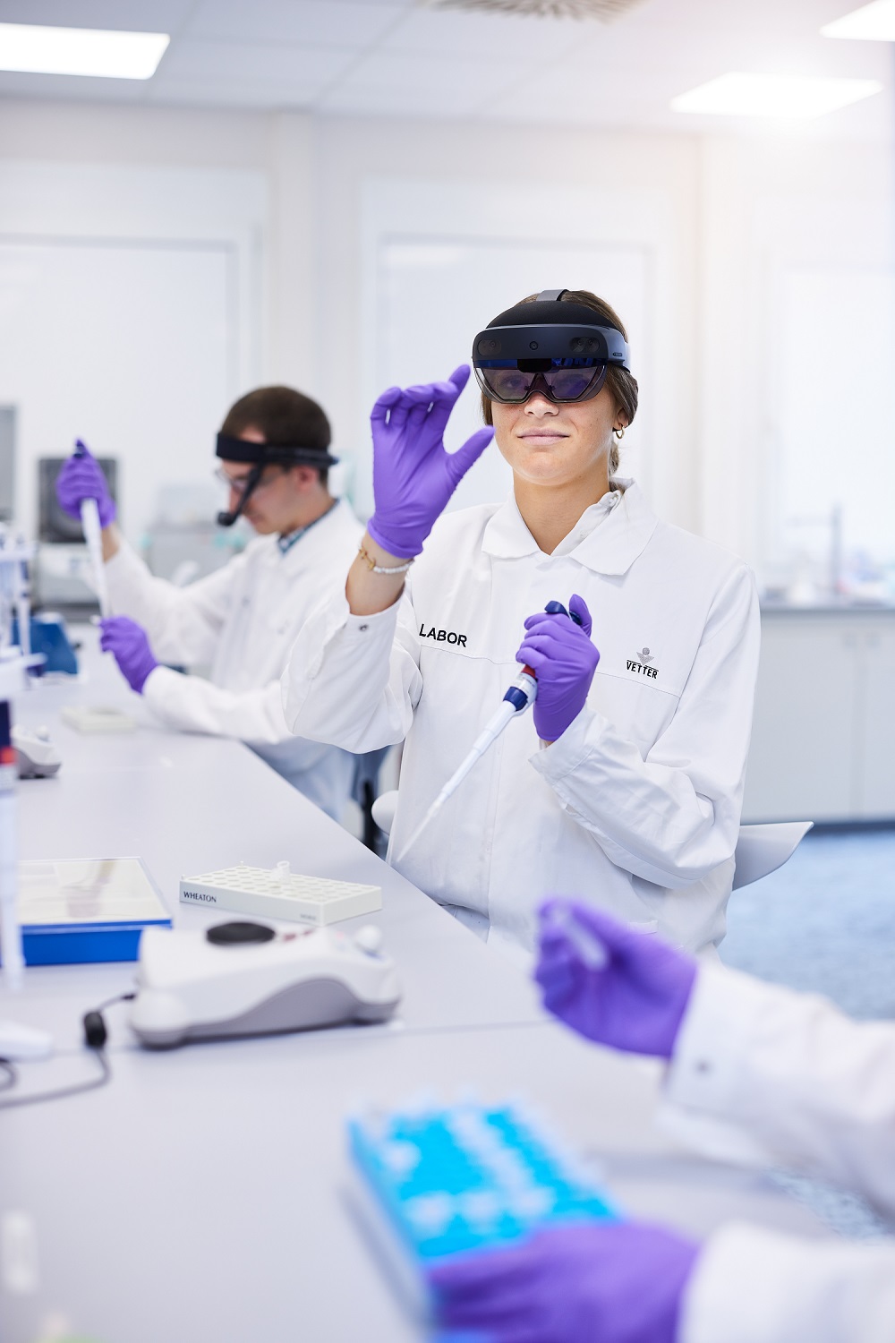 Eine Mitarbeiterin in der Qualitätskontrolle schaut im Labor durch eine AR-Brille