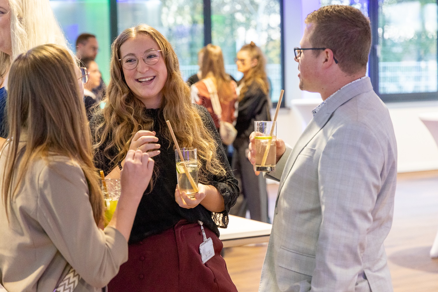 Drei lachende Teilnehmer mit einem Getränk in der Hand 