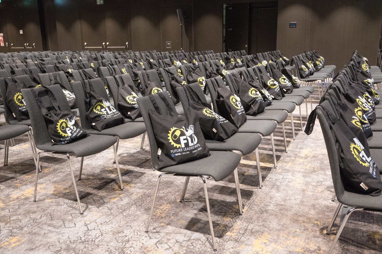 Bestuhlter Konferenzraum, auf jedem Stuhl liegt eine schwarze Tasche mit dem Logo ‚Future Leaders Days‘