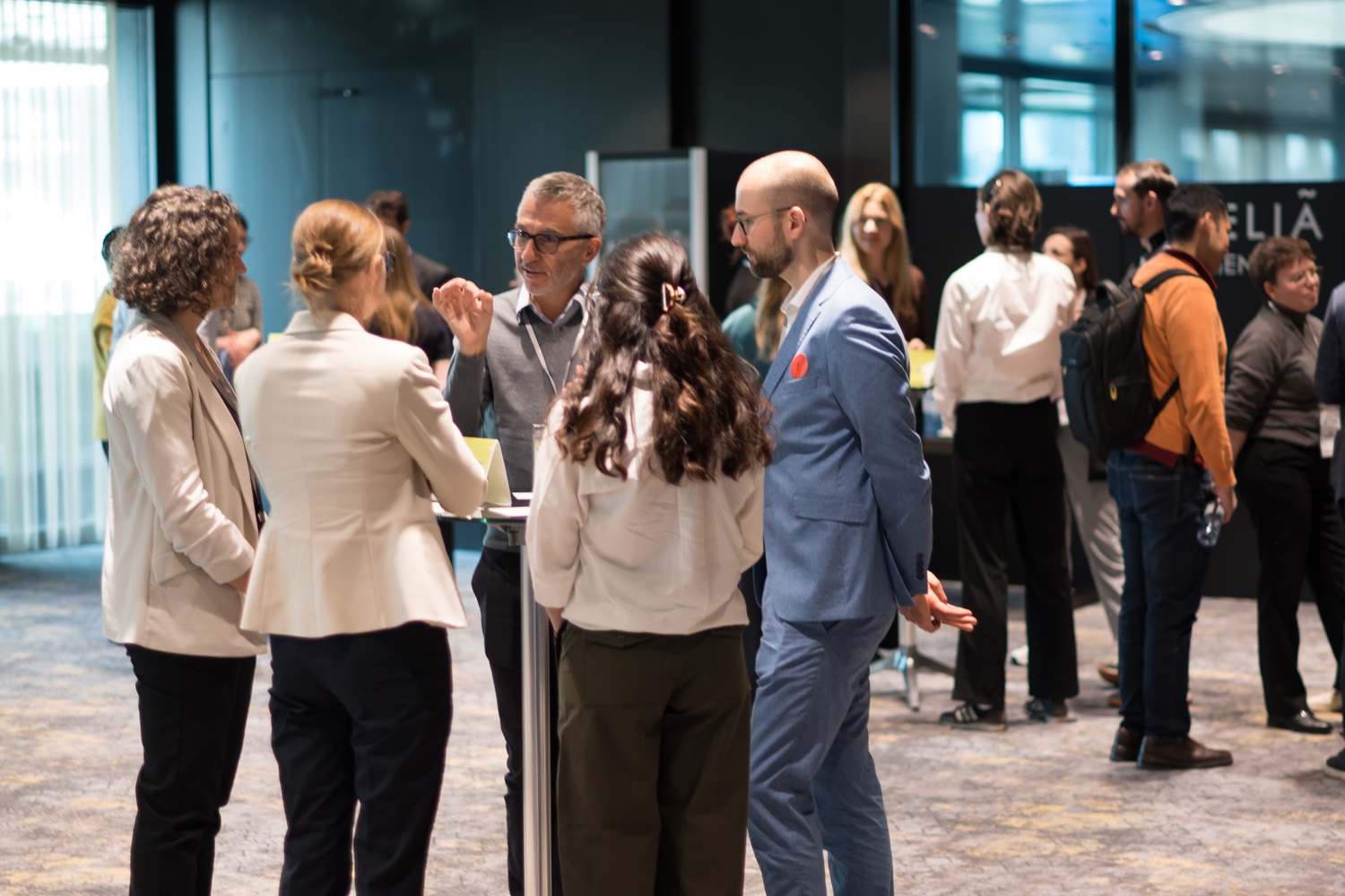 Personengruppen stehen in Konferenzbereich und unterhalten sich