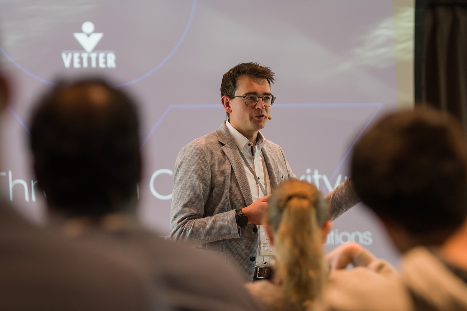 Person spricht während einer Präsentation vor Publikum, im Hintergrund ist eine Folie mit dem Logo ‚Vetter‘ sichtbar