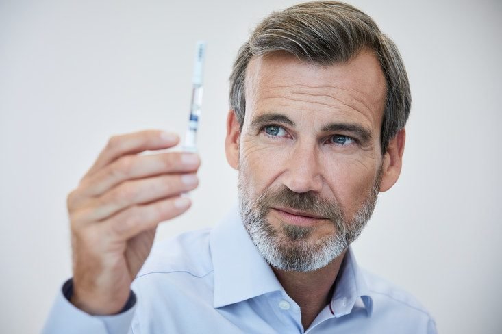 Man is closely looking at a syringe