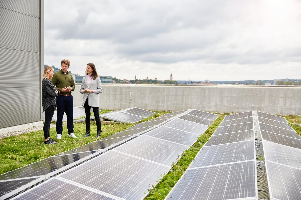Mitarbeitende stehen zwischen Solar-Panelen auf dem Dach eines Vetter-Gebäudes